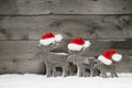 Three mooses wearing santa hats on grey wooden bac Royalty Free Stock Photo