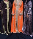 Three Moroccan women wear traditional Moroccan caftans.