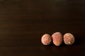 Three mouldy lychees on dark timber background