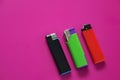 Three multi-colored lighters on a purple background. Gas lighters in black, green and red on the right and plenty of Royalty Free Stock Photo