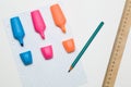 three multi-colored markers, a green pencil, a wooden ruler and a checkered sheet on a white background, supplies for school Royalty Free Stock Photo