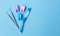 Three multi-colored models of teeth on a blue background. Dental probe. Toothbrush. Place for text. Banner. Flat lay. Lay out.