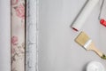 Three multi-colored rolls of wallpaper, a brush, a roller, a container with glue and paint. Apartment renovation concept Royalty Free Stock Photo