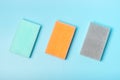 Three multi-colored sponges on blue background, a view from above, a concept of spring cleaning