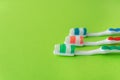 Three multi-colored toothbrushes on a light green background. Oral care concept. Place for inscriptions Royalty Free Stock Photo