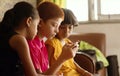 Three multi ethnic kids or siblings busy in playing games on mobile at home - concept of childrens mobile video game