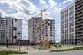 Three multi-storey houses, construction cranes, sports and children`s playground in the newly built area of Eastern Europe.