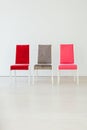 Three multicolored chairs in the interior of an empty white room