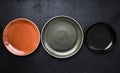 Three multicolored empty plates on black background in close-up