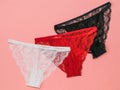 Three multicolored women`s panties on a bright red background. Underwear. The view from the top.