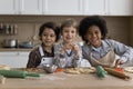 Three multiethnic boys in aprons cooking together in kitchen