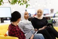 Three multiethnic female colleagues talking in a modern office space