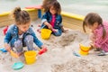 three multiethnic little children playing with plastic scoops and buckets in sandbox