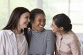 Three multiethnic millennial women, best friends gathered indoor enjoy meeting