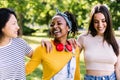 Three multiracial best woman friends laughing together in public park Royalty Free Stock Photo