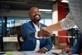 Three multiracial business people smiling while shaking hands during meeting in office Royalty Free Stock Photo