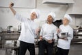 Three multiracial chef cooks take selfie photo on phone in restaurant kitchen Royalty Free Stock Photo