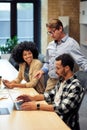 Three multiracial colleagues working together in the modern office, looking at laptop screen and discussing something Royalty Free Stock Photo