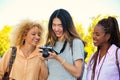 Three multiracial friends looking at the photos in a camera in Madrid, Spain.