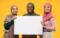 Three Muslim Women Holding Empty Poster Standing Over Yellow Background Royalty Free Stock Photo