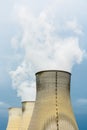 Three cooling towers of a nuclear power plant releasing vapor against a stormy sky