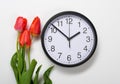 Three natural tulips flowers and clock on white background - time, love and holiday concept Royalty Free Stock Photo