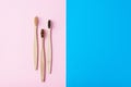 Three natural wooden toothbrushes on a blue and pink color background, flat lay top view. Concept of zero waste and dental care Royalty Free Stock Photo