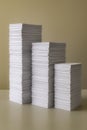 Three neat stacks of white paper of varying heights are shown against a muted, solid background. office or environment design Royalty Free Stock Photo