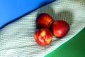 Three nectarines next to a towel on a green and blue background