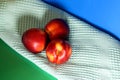 Three nectarines next to a towel on a green and blue background. Shadow in the form of a heart