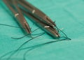 Three needle holders and needles with sutures