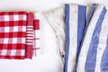 Three new red checkered kitchen picnic towels folded versus old dirty torn blue cloth towels. Cleaning and regularly changing