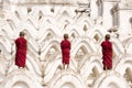 Three novices stand back on the white pagoda in Burma.