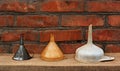 Three old fashioned funnels from metal and plastic on rustic woo