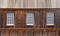 Three old glass windows in a wood wall, rustic wood roof.