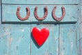 Three old rusty horseshoe luck symbol and red heart on door Royalty Free Stock Photo