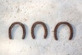 Three old rusty horseshoes hanging on a white wall, luck symbol