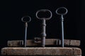 Three old rusty keys stand on old wooden board against a dark background Royalty Free Stock Photo
