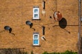 Three old satellite dishes mounted to the outside brick wall with two windows of a residential building Royalty Free Stock Photo