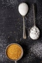 Three old spoons with brown, white and icing sugar on black background Royalty Free Stock Photo