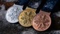 Three Olympic medals laying on the snow. Generative AI Royalty Free Stock Photo