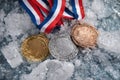 Three Olympic medals laying on the snow. Generative AI. Royalty Free Stock Photo