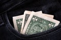 Three one dollar banknotes stick out in the pocket of black jeans.