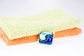 Three in one eco gel capsule laundry detergent in front of two towels Royalty Free Stock Photo