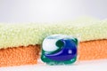 Three in one eco gel capsule laundry detergent in front of two towels Royalty Free Stock Photo