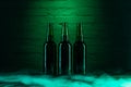 three open green beer bottles and smoke in green