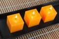 Three orange candles in black dish