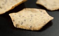 Three organic grain crackers on black, selective focus. Close-up