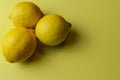 Three organic lemons from sicily siracusa on a light yellow paper background with plenty of room for text