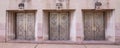 Three ornate metal doors with concrete sculpture masks